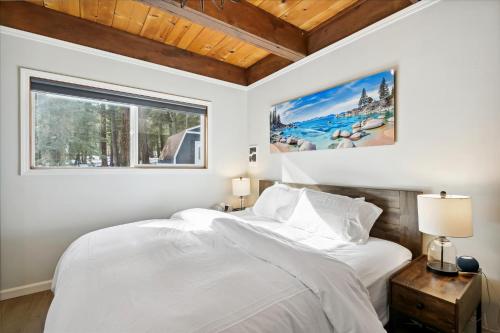 een witte slaapkamer met een groot bed en een raam bij Cobalt Cabin - Beautifully remodeled 3BR with private hot tub, fireplace and dogs ok in Carnelian Bay