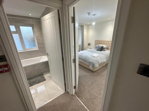 5 bedroom house in Orpington في أوربنغتون: غرفة نوم مع سرير وحوض استحمام بجوار نافذة