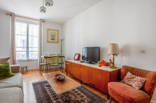uma sala de estar com um sofá e uma televisão em Charming Parisian flat in the 11th arrondissement - Welkeys em Paris