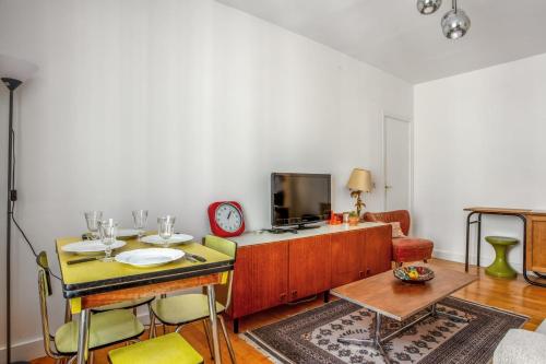 uma sala de estar com uma mesa e uma televisão em Charming Parisian flat in the 11th arrondissement - Welkeys em Paris