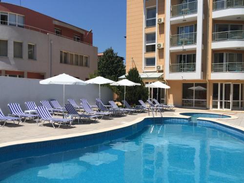 uma piscina com cadeiras e guarda-sóis ao lado de um edifício em Sunny Residence Complex em Sunny Beach