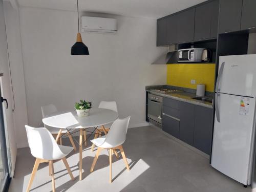 een keuken met een tafel en stoelen en een witte koelkast bij Monoambiente Plaza Mitre in Mar del Plata