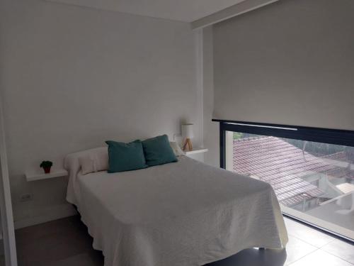 Dormitorio blanco con cama y ventana en Monoambiente Plaza Mitre en Mar del Plata