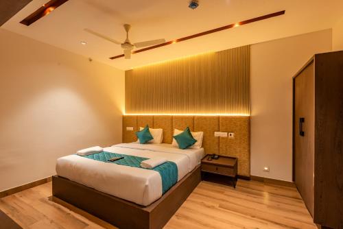 a bedroom with a large bed with blue pillows at Hotel Stay Bella Kozhikode in Kozhikode