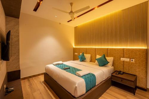 a bedroom with a large bed with green pillows at Hotel Stay Bella Kozhikode in Kozhikode