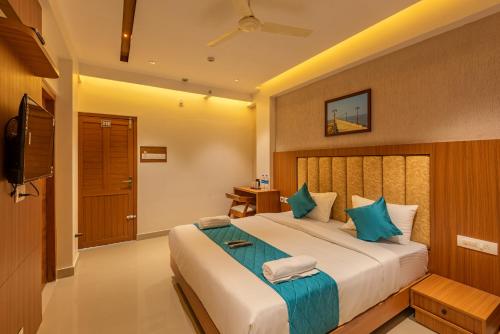 a bedroom with a large bed and a flat screen tv at Hotel Stay Bella Kozhikode in Kozhikode