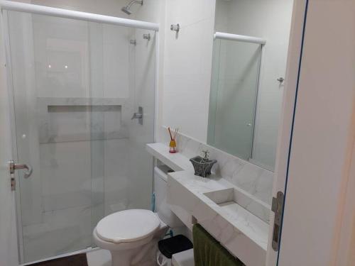 een witte badkamer met een toilet en een douche bij Ótimo Apto, Jacuzzi aquecida e piscina, pertinho da praia in Bombinhas