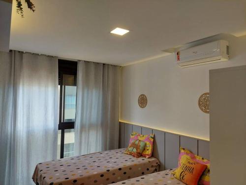 a small bedroom with two beds and a window at Ótimo Apto, Jacuzzi aquecida e piscina, pertinho da praia in Bombinhas