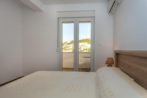 a white bedroom with a bed and a window at Butique Maris in Komarna