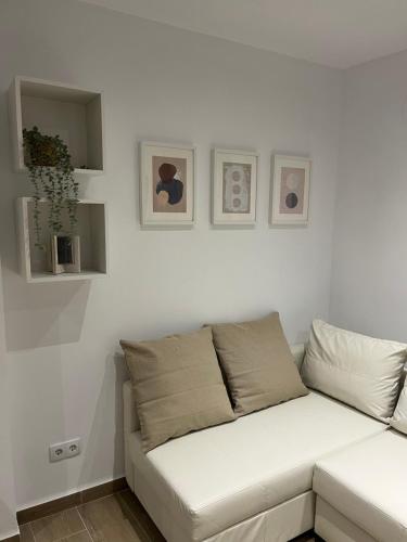 a white couch in a living room with pictures on the wall at CASA MARTÍN in Hornachuelos