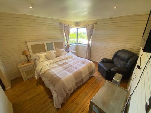 Un dormitorio con una cama y una silla de cuero negro en Casa de Campo con Piscina - Panimávida, en Colbún