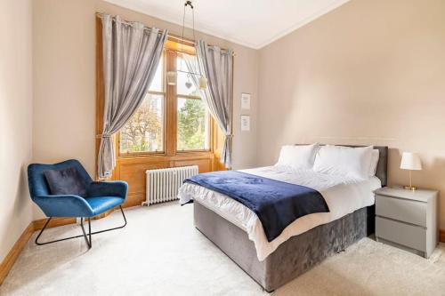 um quarto com uma cama e uma cadeira azul em Lady Road Apartment em Edimburgo