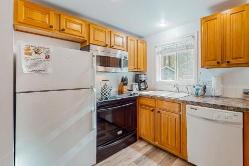 a kitchen with a white refrigerator and wooden cabinets at Alder Creek A-Frame in Sandy