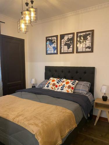 1 dormitorio con 1 cama y 3 cuadros en la pared en Hostal El Raco, en Santiago