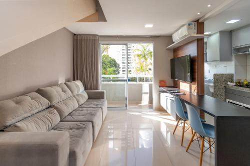 sala de estar con sofá grande y cocina en Lindos Flats no Setor Bueno TXP02, en Goiânia