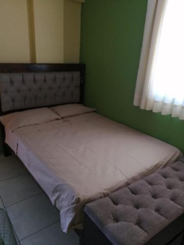 a bed in a bedroom with a green wall at Hostal Boulevard in Nazca