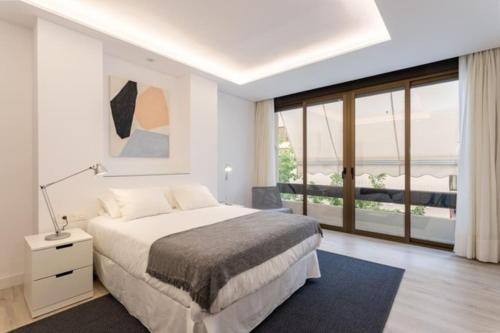 a white bedroom with a bed and a large window at Ap. Marbella centro in Marbella