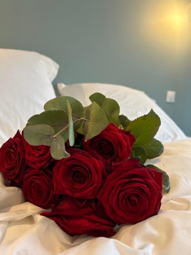 a bouquet of red roses sitting on a bed at La Belle Vicoise in Vic-sur-Aisne