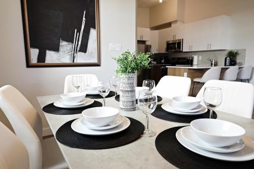 een eettafel met witte borden en wijnglazen bij Central 5 Bedroom,Rogers,Commonwealth,NAIT in Edmonton