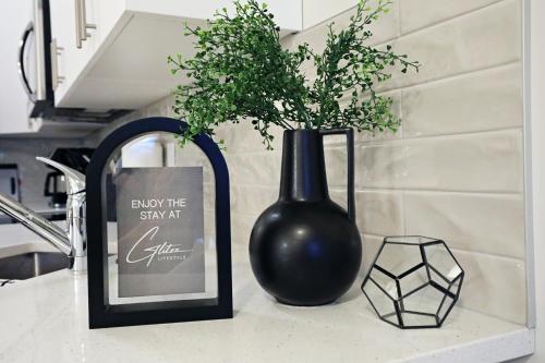 a black vase sitting on a counter with a sign and a plant at Central 5 Bedroom, AC, Rogers, Commonwealth, EXPO in Edmonton