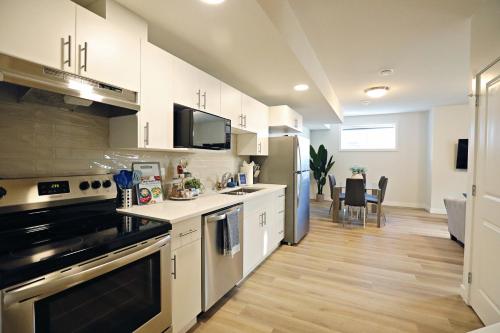 a kitchen with white cabinets and a dining room at Central Suite King Beds,Long Stays,Disney+ in Edmonton