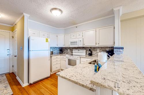 uma cozinha com armários brancos e um frigorífico branco em Sight of the Sea em Myrtle Beach