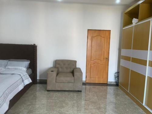 ein Schlafzimmer mit einem Bett und einem Stuhl neben einer Tür in der Unterkunft 4-bedroom City view Town House Accra in Accra