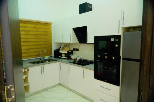 une cuisine avec des armoires blanches et des appareils noirs dans l'établissement Crown Exquisite Magodo Phase 2 - 3 bedroom 03, à Lagos