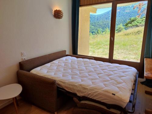 un lit dans une chambre avec une grande fenêtre dans l'établissement Appartement Les Cimes, à Gresse-en-Vercors