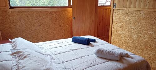 Cabañas Caiquen La Junta في La Junta: غرفة نوم عليها سرير ومخدة زرقاء