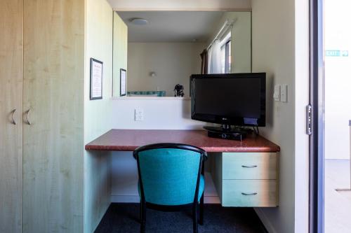 a room with a desk with a monitor and a chair at Bella Vista Motel Wellington in Wellington