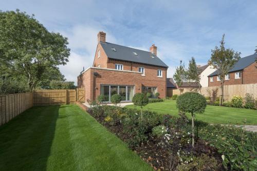 een groot bakstenen huis met een groene tuin bij The Heyford Hotel in Upper Heyford