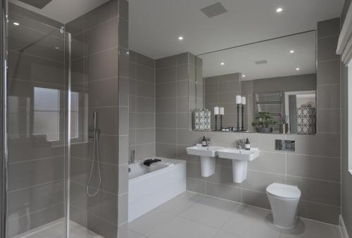 a bathroom with two sinks a toilet and a shower at The Heyford Hotel in Upper Heyford
