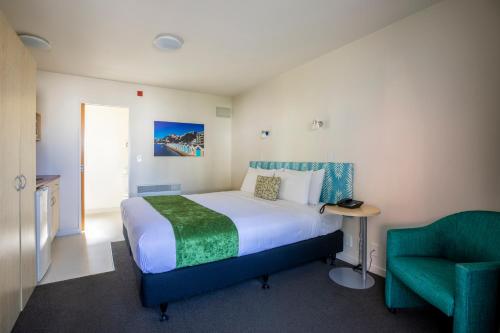 a bedroom with a bed and a green chair at Bella Vista Motel Wellington in Wellington