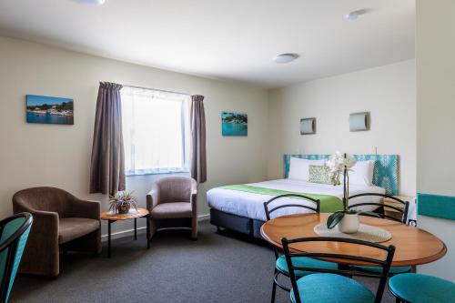 a hotel room with a bed and a table and chairs at Bella Vista Motel Wellington in Wellington