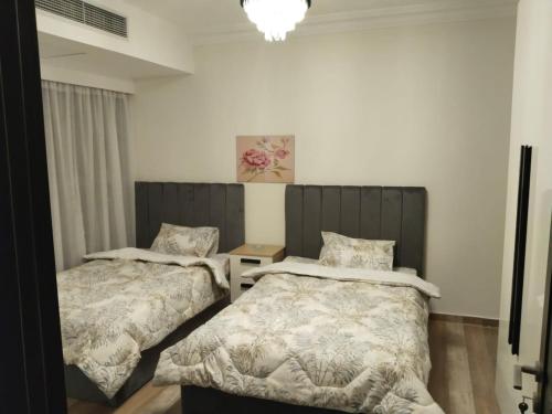 a bedroom with two beds and a chandelier at Best view , New furniture Gameat Al Dewal Al Arbeya in Cairo