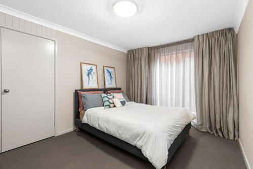 a bedroom with a bed and a large window at Denhams Beach Waterfront in Surf Beach