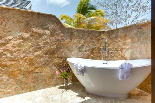 a bath tub in a bathroom with a stone wall at The Enclave - Your Own Private Island Retreat in Placencia Village