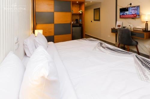 a bedroom with a large white bed and a desk at Khan Duidar Inn - Pyramids View Rooftop in Cairo