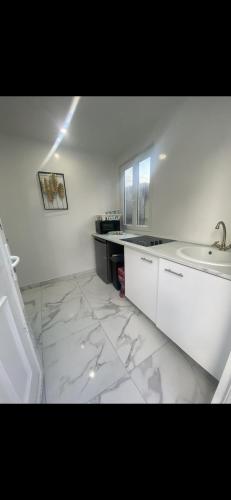 a white kitchen with a sink and a counter at Appartement beau in Drancy