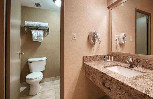 two pictures of a bathroom with a toilet and a sink at Best Western Plus Durham Hotel & Conference Centre in Oshawa