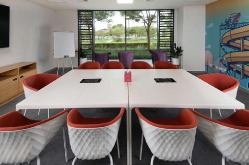 a conference room with a white table and red chairs at Rove At The Park in Dubai