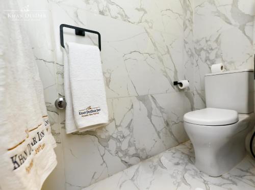 a white bathroom with a toilet and marble walls at Khan Duidar Inn - Pyramids View Rooftop in Cairo