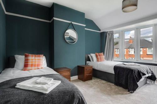 a bedroom with two beds with blue walls and a mirror at Charming 3BD Home Didsbury House in Manchester