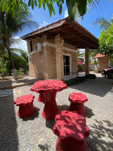 a group of red tables in front of a building at Chacara do Alemao in Flecheiras