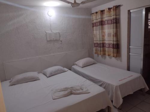 2 Einzelbetten in einem Zimmer mit Fenster in der Unterkunft HOTEL ITAVERÁ BRASIL in Presidente Prudente