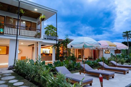 a patio with lounge chairs and umbrellas in front of a building at Cannatel Exclusive Hotel in La Tebaida