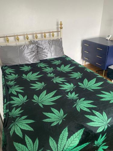 a bed with a black and green leafy comforter at Elegant single-occupancy double bed room(1 person only) in Morriston