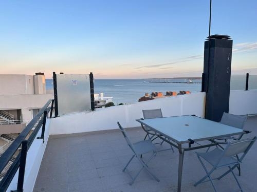 einen Tisch und Stühle auf einem Balkon mit Meerblick in der Unterkunft Departamento frente al mar. Terraza y cochera privadas. Parrilla. in Puerto Madryn