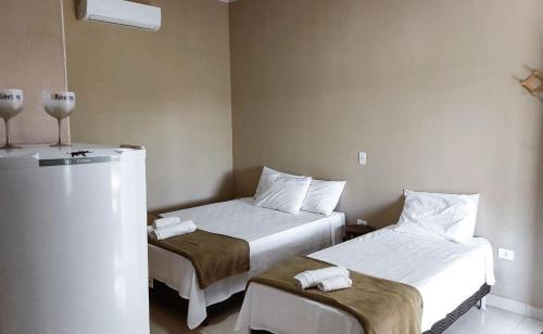 Cette chambre comprend deux lits et un réfrigérateur. dans l'établissement Sítio Rupestre - Peruaçu, à Januária